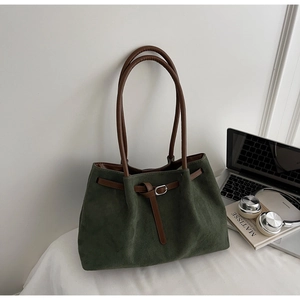 Detail of dark green suede tote bag with brown leather straps and silver metal hardware