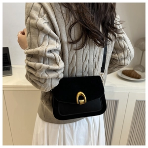 Detail view of a vintage black leather crossbody bag with a gold U-shaped metal buckle