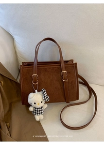 Dettaglio borsa a mano marrone vintage con un ciondolo di peluche Hello Kitty