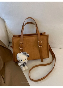 Dettaglio borsa retrò in pelle marrone con cinturini a fibbia e ciondolo di peluche