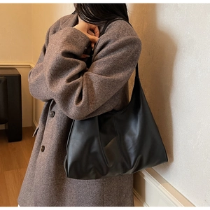 Detail view of a large black hobo shoulder bag in soft leather on a model's shoulder