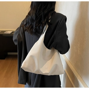 Detail shot of a white minimalist half-moon hobo bag on a black blazer with premium leather texture