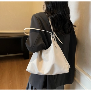 Detailed side view of a large white minimalist leather tote bag worn by a model