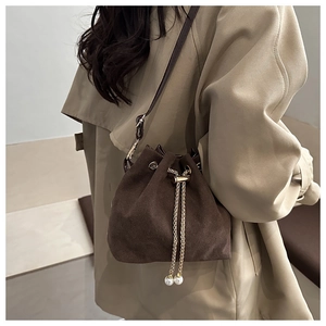Close-up of dark brown suede drawstring bucket bag with gold chain and pearl charms