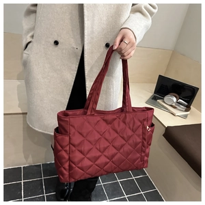 Detail of burgundy quilted tote bag with side pocket and sleek nylon texture on model