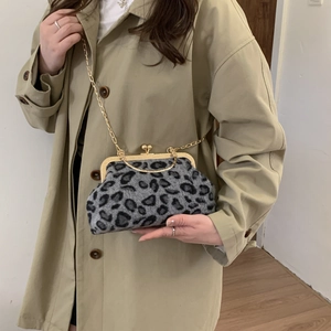 Elegant leopard print shell bag with gold chain strap shown on a beige trench coat