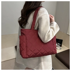 Detail of red quilted nylon tote bag with side pocket shown on a female model