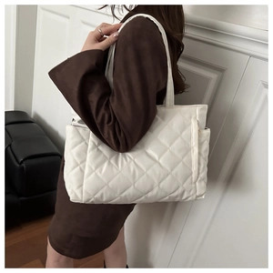 Detail of white quilted tote bag showing large capacity and soft puff texture on shoulder
