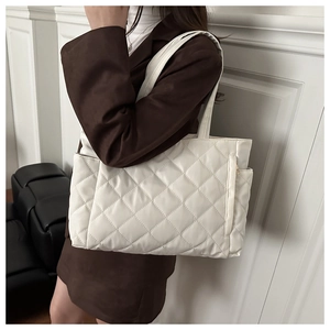 Detail of white quilted tote bag featuring a side zipper pocket and elegant diamond stitching