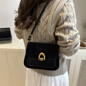 Classic black crossbody bag with gold horseshoe clasp shown on model in modern room
