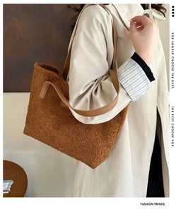 Detail of brown sherpa tote bag with faux leather strap worn with a beige trench coat