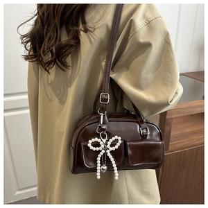 Detail of retro brown underarm bag with beaded bow pendant and shiny leather texture