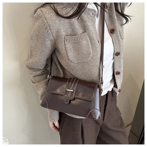 Detail der dunkelbraunen Retro-Umhängetasche in Lackoptik getragen zum Strickoutfit