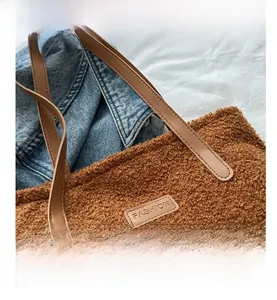 Detail view of brown teddy plush tote bag featuring a leather FASHION label and stitching