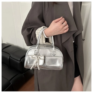 Detail showing silver metallic shoulder bag with pearl bow charms and square front pockets