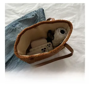 Spacious interior of a brown teddy fur tote bag showing phone, wallet and umbrella