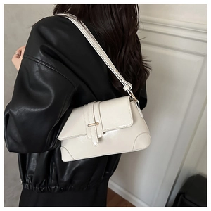 Schicke cremefarbene Schultertasche an einem Model in schwarzer Jacke für modernen Stil