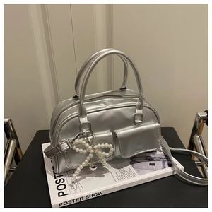 Detailed view of silver metallic Boston bag with pearl bow charm and dual front pockets