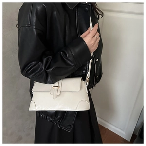 Détail du sac porté épaule crème vintage avec boucle dorée et bandoulière en cuir