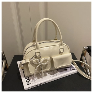 Detail of cream Boston bag featuring beaded bow charm and smooth leather texture