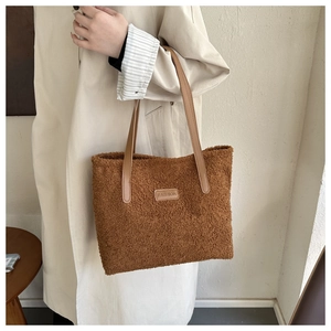 Detail of brown plush tote bag showing fuzzy lamb wool texture and FASHION leather patch