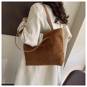 Close-up of a large brown plush tote bag with FASHION leather patch and slim straps