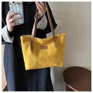 Detail of yellow fuzzy fleece tote bag showing plush texture and brown leather handles