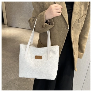 Detail of white fluffy plush tote bag with FASHION patch and leather strap for women