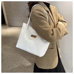 Detail of white plush tote bag with brown leather FASHION tag and slim shoulder strap