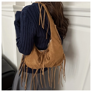Détail du sac bandoulière en daim marron avec de longues franges bohèmes et texture vintage