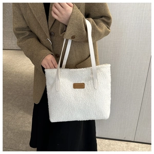 Detail view of white plush tote bag with brown fashion leather patch and straps