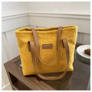 Detail of yellow fuzzy fleece tote bag with brown faux leather straps and FASHION label