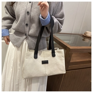 Chic cream canvas tote bag with contrast black handles shown in a lifestyle setting