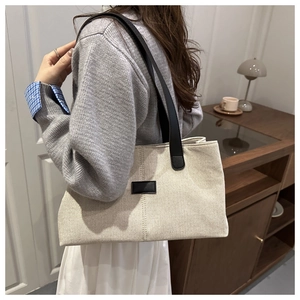 Détail du sac cabas en toile beige avec anses en cuir noir et texture cousue