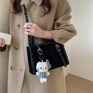 Borsa a tracolla nera retrò con ciondolo di peluche su modella in cappotto cammello