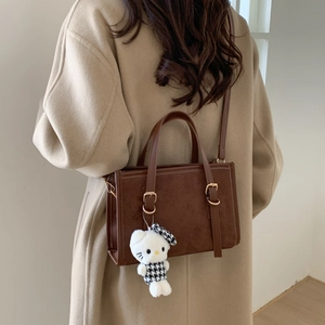 Borsa a mano retrò in pelle opaca marrone con ciondolo indossata da una modella