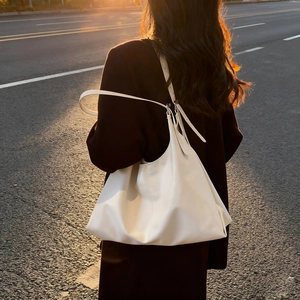 Minimalist off-white large capacity leather tote bag worn by model on shoulder outdoors