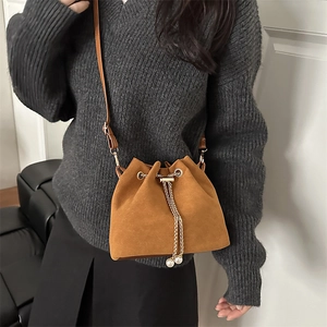 Brown suede bucket bag with gold chain and pearl charms worn over grey sweater