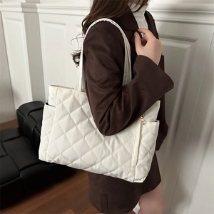 White quilted tote bag for women featuring classic diamond patterns and side pockets