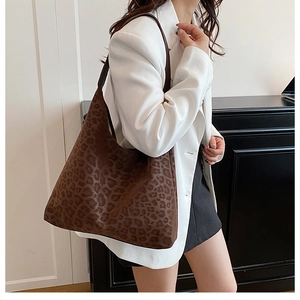 Close-up of leopard print tote bag with soft suede texture styled on a white blazer