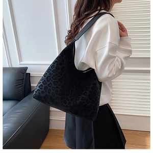 Detailed view of black leopard print tote bag with plush texture on female model
