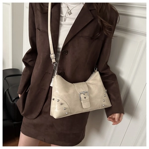 Detailed macro view of beige vintage tote bag featuring decorative buckles and metal rivets