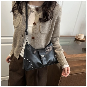 Detail of a black punk tote bag with silver studs and metal buckle on a model