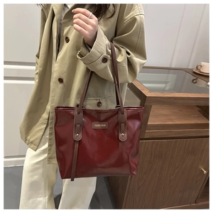 Close-up of a burgundy patent leather tote bag featuring a Fashion & Bags logo patch