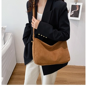 Close-up of brown suede hobo bag with large capacity worn by a model in casual style