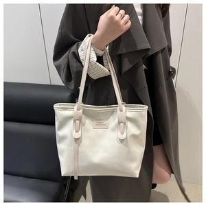 Detail of white leather tote bag with Fashion & Bags patch and slender shoulder straps