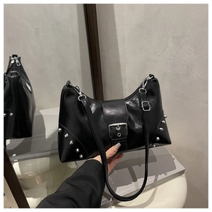 Close-up of black glossy shoulder bag featuring silver rivets and metal buckle detail