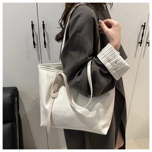 Detail of a white patent leather tote bag showing glossy texture and gold hardware details