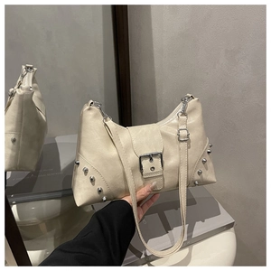 Close-up of cream textured faux leather bag with silver rivets and metal buckle detail