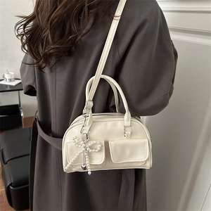 Vintage cream-white underarm bag with beaded bow and heart pendant on brown coat model